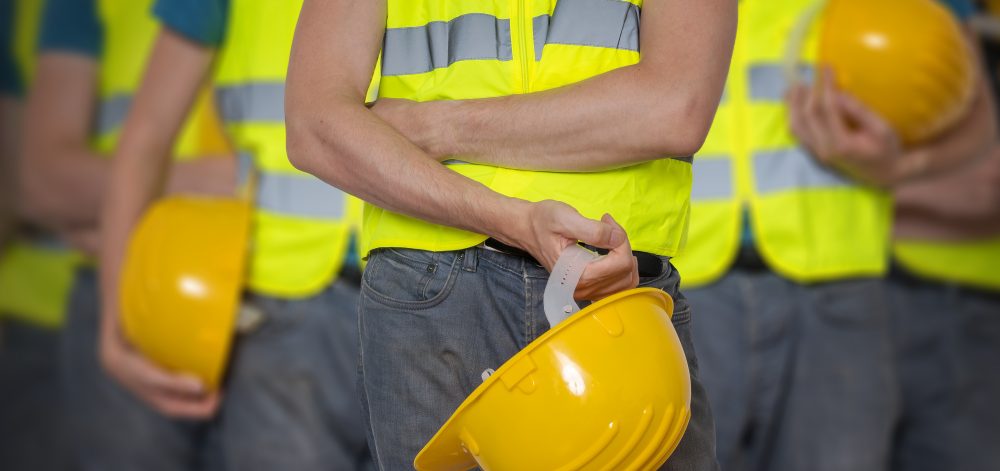 Many workers in vest with protective helmet.